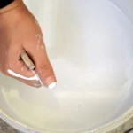 emmer met plastisol en een hand die de vloeistof roert
